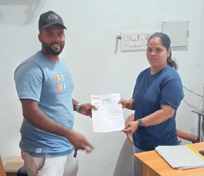 Two individuals standing indoors, one of them holding an official document in their hands.